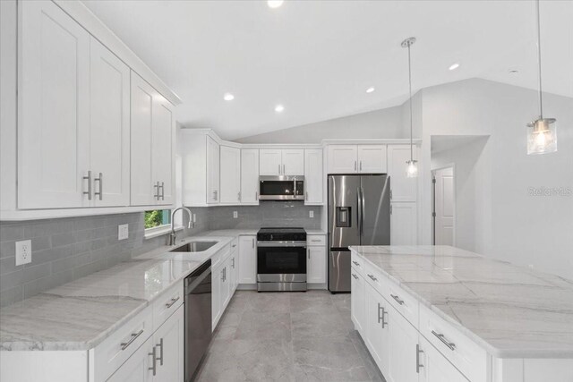 kitchen with light tile patterned flooring, vaulted ceiling, stainless steel appliances, decorative light fixtures, and sink