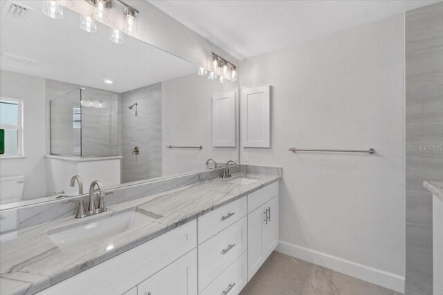 bathroom featuring dual vanity, toilet, and tile patterned floors