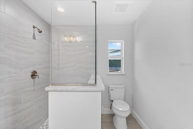 bathroom featuring tiled shower, tile patterned floors, and toilet