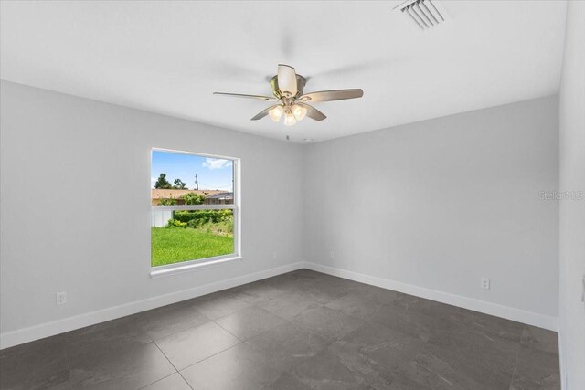 tiled spare room featuring ceiling fan