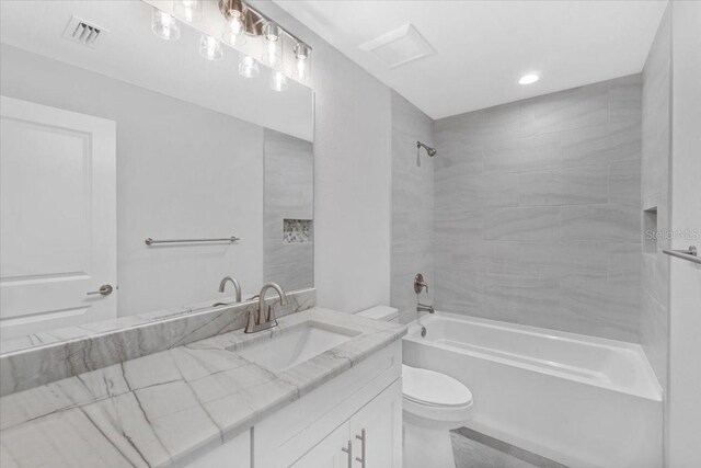 full bathroom featuring vanity, tiled shower / bath, and toilet