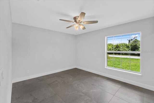 tiled spare room featuring ceiling fan