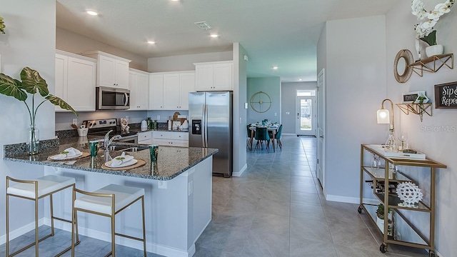 4067 NW 44th Cir, Ocala, FL 34482 - kitchen with stainless steel appliances, dark stone countertops, a peninsula, white cabinets, and baseboards