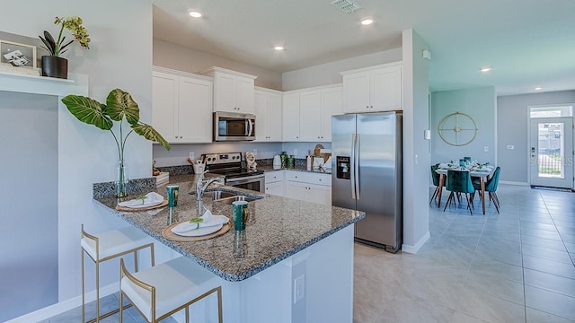 4067 NW 44th Cir, Ocala, FL 34482 - kitchen featuring stainless steel appliances, dark stone countertops, a peninsula, white cabinets, and baseboards