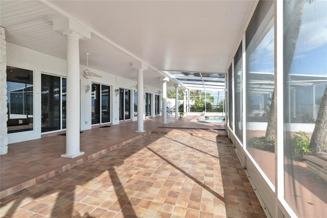 unfurnished sunroom with decorative columns, a swimming pool, and ceiling fan