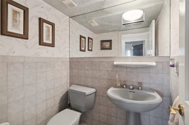 bathroom with toilet and tile walls