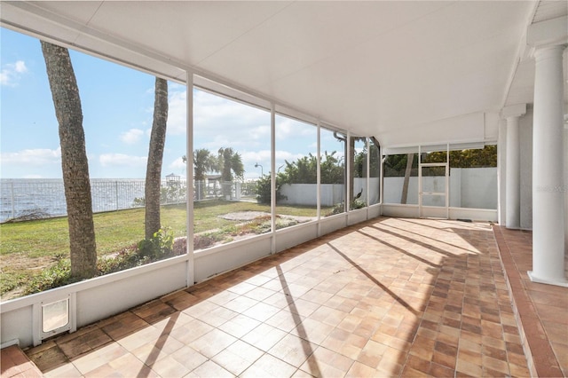 unfurnished sunroom with decorative columns and a water view