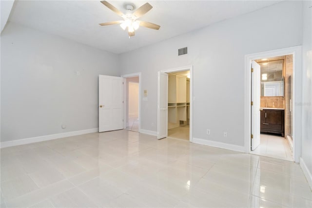 unfurnished bedroom with a spacious closet, connected bathroom, a closet, and light tile patterned floors