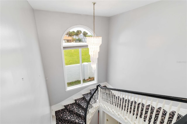 stairs featuring a chandelier