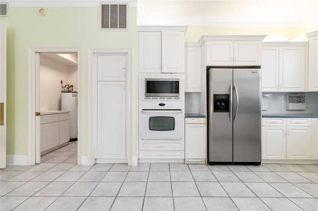 kitchen with water heater, white cabinets, stainless steel appliances, and light tile patterned floors