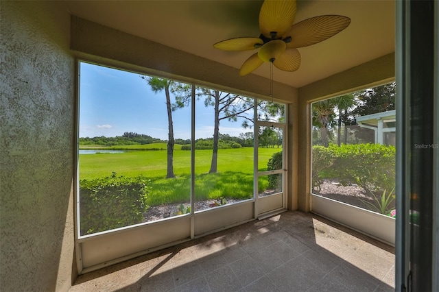 unfurnished sunroom with ceiling fan and a water view