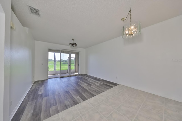 spare room featuring hardwood / wood-style flooring, a notable chandelier, and a textured ceiling