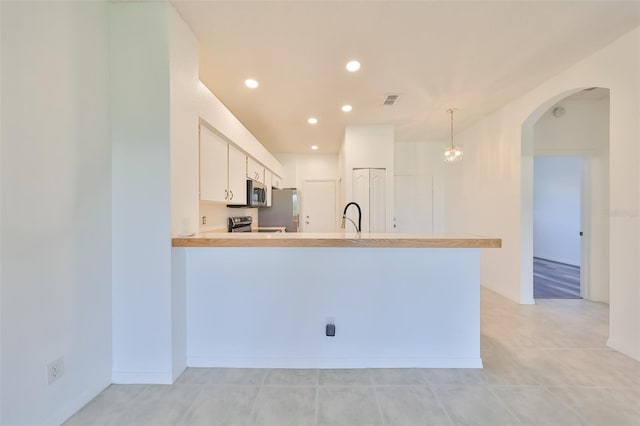 kitchen with sink, decorative light fixtures, appliances with stainless steel finishes, kitchen peninsula, and white cabinets