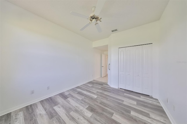 unfurnished bedroom featuring ceiling fan, light hardwood / wood-style floors, and a closet