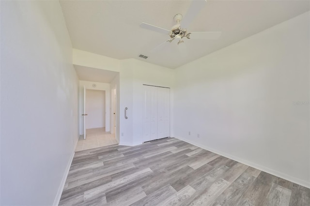 unfurnished bedroom featuring light hardwood / wood-style flooring, a closet, and ceiling fan