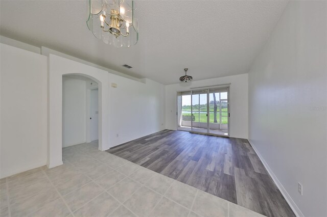 633 Tremont Greens Ln Unit 16, Sun City Center, FL 33573 - unfurnished room featuring arched walkways, a chandelier, a textured ceiling, and wood finished floors