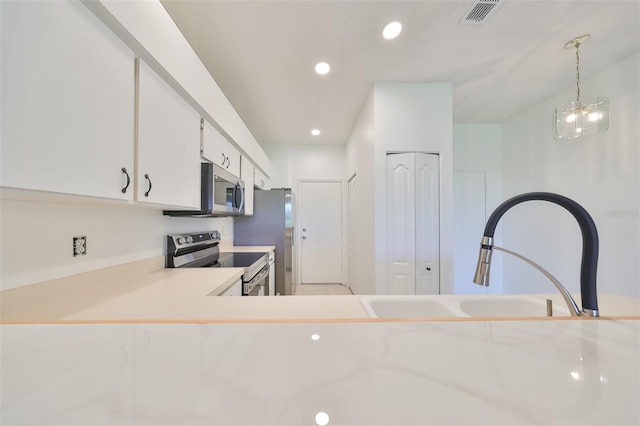 kitchen featuring pendant lighting, sink, white cabinets, and appliances with stainless steel finishes