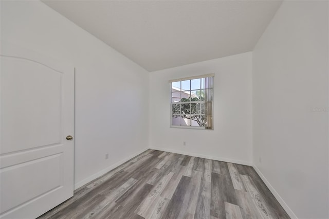 empty room featuring wood-type flooring and vaulted ceiling