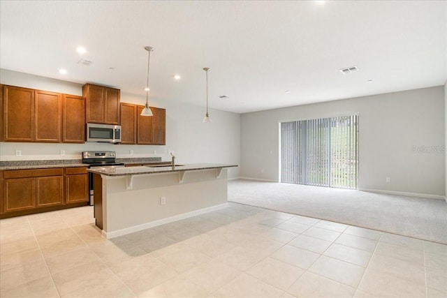 kitchen featuring hanging light fixtures, a breakfast bar, stainless steel appliances, a center island with sink, and sink