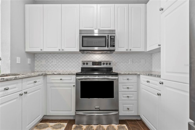 kitchen with sink, light stone counters, stainless steel appliances, and white cabinetry