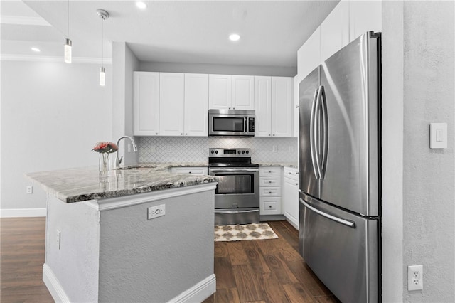 kitchen featuring pendant lighting, kitchen peninsula, sink, white cabinetry, and appliances with stainless steel finishes