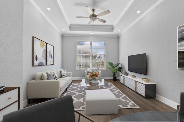 living room with crown molding, ceiling fan, dark hardwood / wood-style flooring, and a tray ceiling