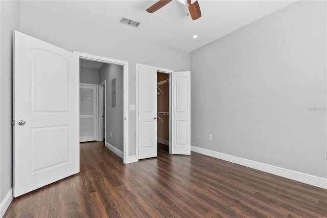 unfurnished bedroom with ceiling fan, a spacious closet, dark hardwood / wood-style flooring, and a closet