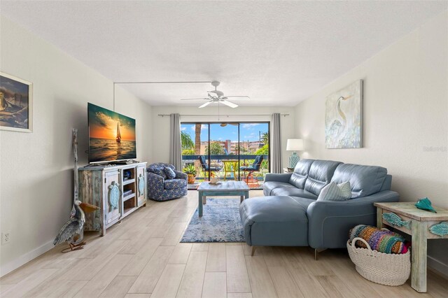 living room featuring ceiling fan, a textured ceiling, and light hardwood / wood-style flooring