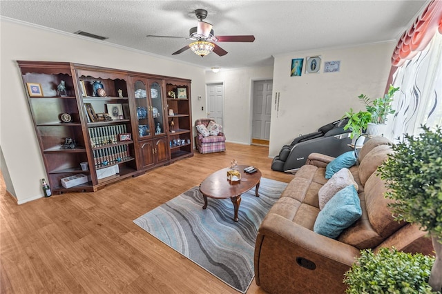 living room with ceiling fan, wood-type flooring, a textured ceiling, and ornamental molding