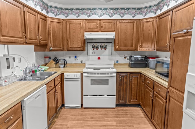 kitchen with tasteful backsplash, white appliances, crown molding, sink, and light hardwood / wood-style flooring