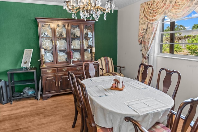 dining room with a chandelier, light wood-type flooring, and ornamental molding