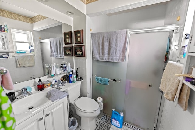 bathroom featuring a shower with door, vanity, tile walls, and toilet