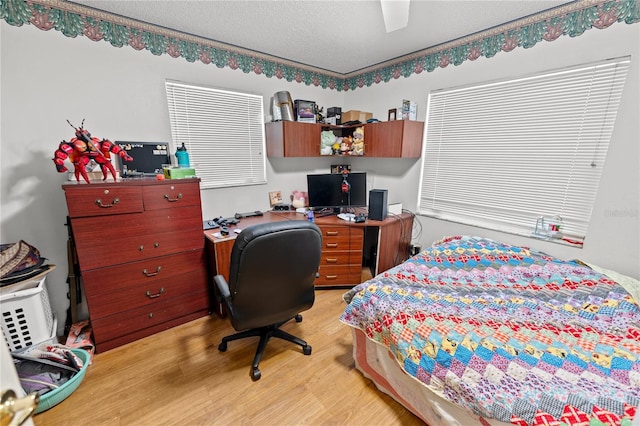 bedroom with a textured ceiling, light wood-type flooring, and ceiling fan