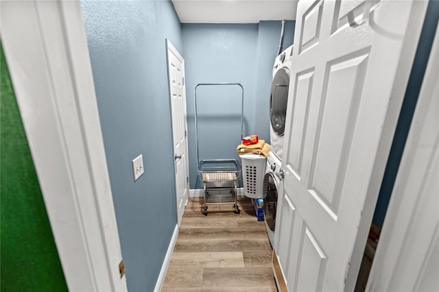 clothes washing area with light wood-type flooring and stacked washer and dryer