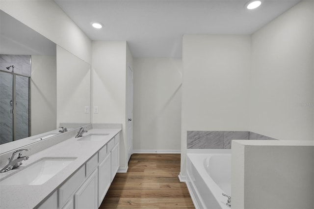 bathroom with dual vanity, shower with separate bathtub, and hardwood / wood-style flooring