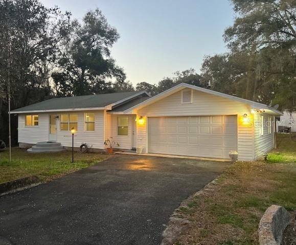 single story home featuring aphalt driveway and a garage