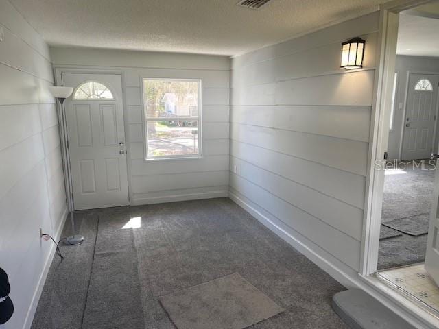 carpeted entrance foyer featuring a textured ceiling