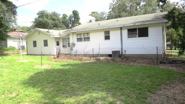 back of house with cooling unit and a lawn