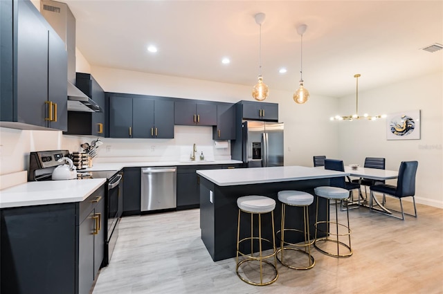 kitchen with light hardwood / wood-style flooring, a kitchen island, appliances with stainless steel finishes, pendant lighting, and sink