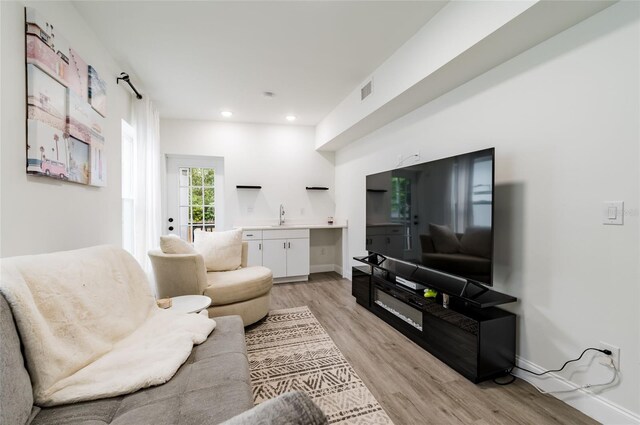 living room featuring sink and light hardwood / wood-style flooring