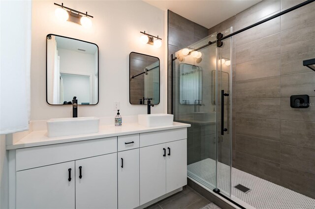 bathroom with a shower with shower door and double vanity