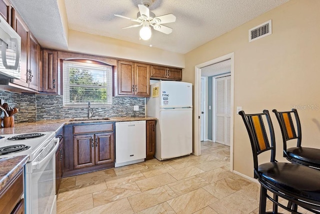 kitchen featuring tasteful backsplash, light tile patterned floors, white appliances, ceiling fan, and sink