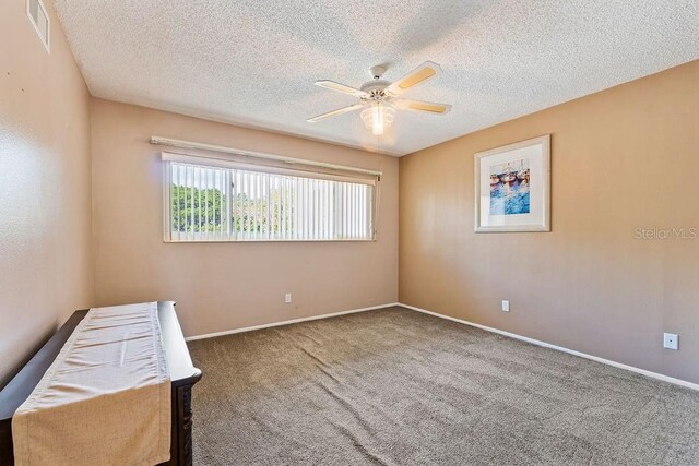 unfurnished bedroom featuring carpet floors, a textured ceiling, and ceiling fan