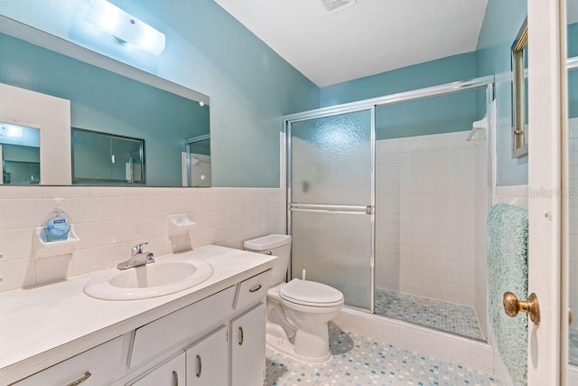 bathroom featuring a shower with shower door, tile walls, backsplash, toilet, and vanity