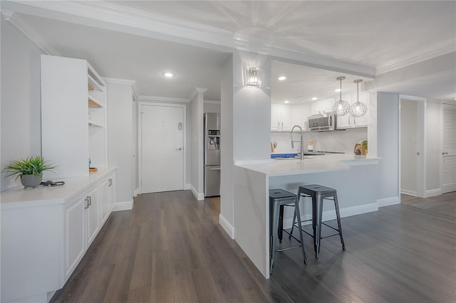 kitchen featuring stainless steel appliances, white cabinetry, ornamental molding, and kitchen peninsula