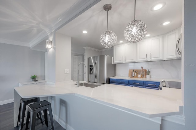 kitchen with stainless steel appliances, white cabinets, blue cabinets, decorative light fixtures, and kitchen peninsula