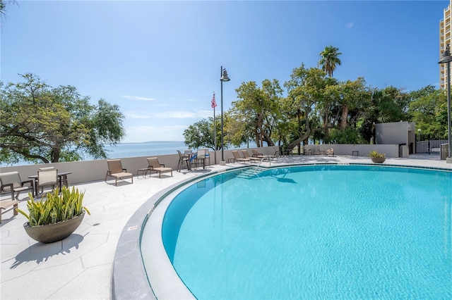 view of pool with a patio and a water view