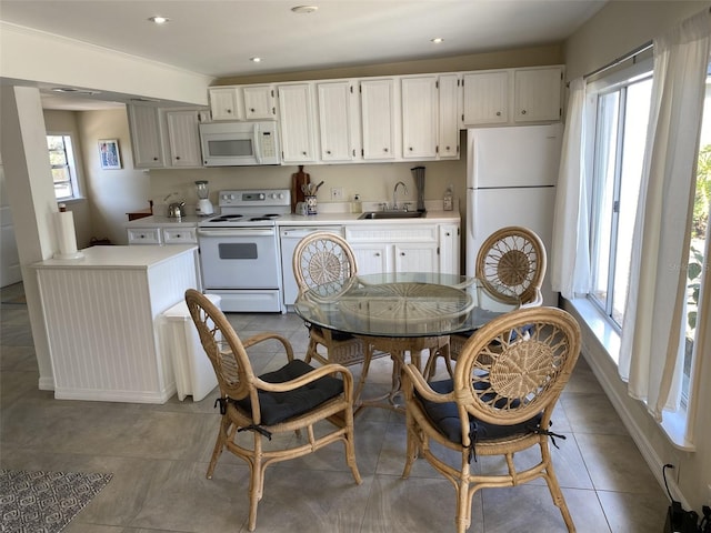 kitchen with a healthy amount of sunlight, tile patterned floors, white appliances, and sink