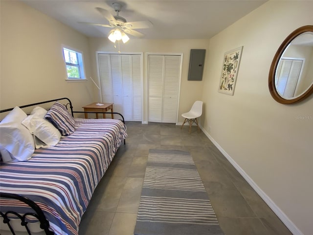 bedroom featuring multiple closets, ceiling fan, dark tile patterned floors, and electric panel