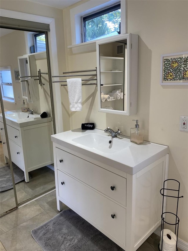 bathroom featuring double vanity, tile patterned flooring, and a wealth of natural light